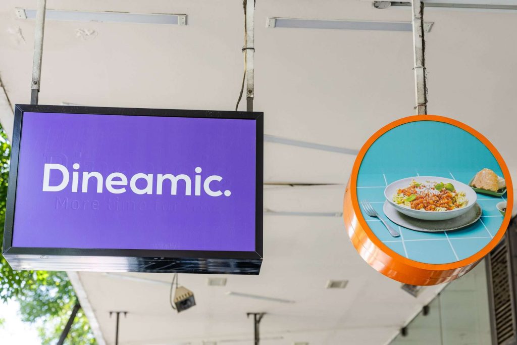 Dineamic Food Store South Yarra purple sign on outside of store along with photo of a plate of food