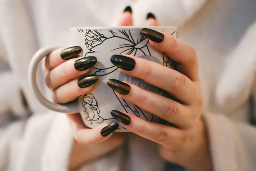 a person holding a cup with manicured nails