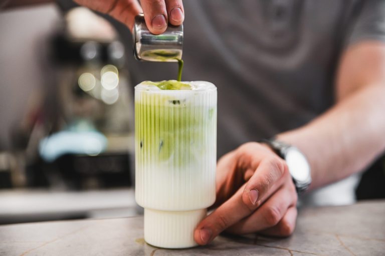 a person pouring green matcha into a glass